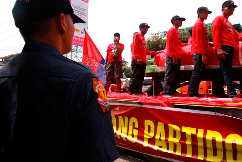 RED GUARDS. A police officer watches the coffin of New People's Army commander Leoncio Pitao, alias Kumander Parago, as Red guards surround the coffin displayed along the highway of Buhangin, Davao City during the funeral caravan.(Ace R. Morandante/davaotoday.com)