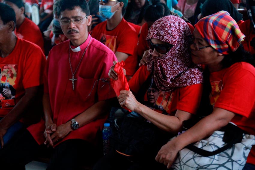 WIFE. Evangeline, wife of slain NPA commander Leoncio Pitao, receives the flag of the Communist Party of the Philippines after the liturgy held at the chapel inside Davao Memorial Park. Beside her is Bishop Jonathan Casimina of the Episcopal Diocese of Davao.(Ace R. Morandante/davaotoday.com)