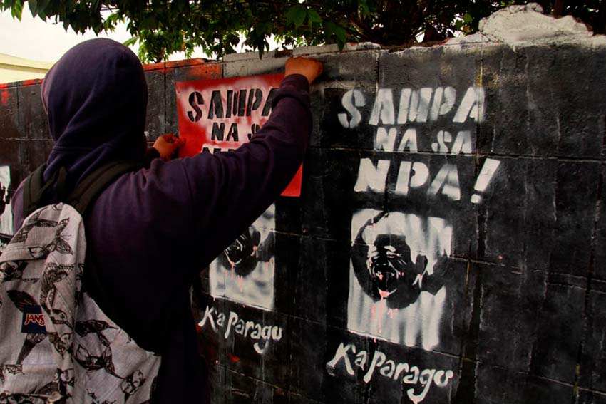 REPAINT. Members of the underground youth movement repaint the graffiti wall along Matina highway in Davao City with images of Kumander Parago and the words Long Live the New People's Army. On Thursday afternoon local artist finished a mural of Kumander Parago, however it was defaced in black paint immediately.(Ace R. Morandante/davaotoday.com)