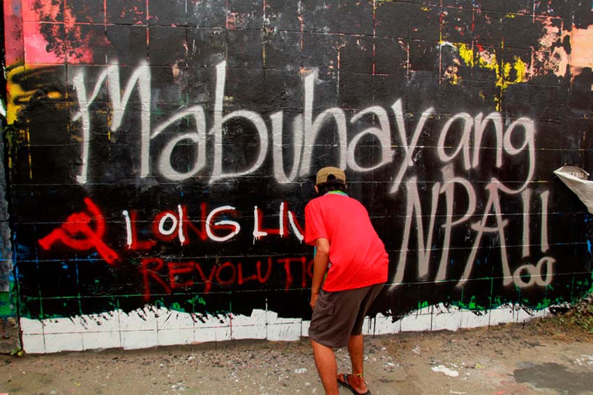 REPAINT. Members of the underground youth movement repaint the graffiti wall along Matina highway in Davao City with images of Kumander Parago and the words Long Live the New People's Army. On Thursday afternoon local artist finished a mural of Kumander Parago, however it was defaced in black paint immediately.(Ace R. Morandante/davaotoday.com)