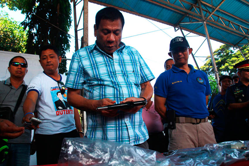 Mayor Rodrigo Duterte checks the confiscated guns owned by the alleged drug pushers rounded-up in a simultaneous raid in Davao City on Wednesday morning. The authorities have confiscated a total of 13 firearms and 10 assorted ammunition. (Ace R. Morandante/davaotoday.com)