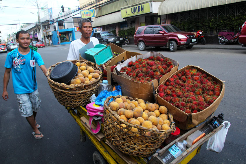 Baskets of fruits are peddled along downtown Davao by these two vendors. Tourists and residents are enjoying fruits in season during the Kadayawan Festival as these are sold at cheap prices. (Ace R. Morandante/davaotoday.com)