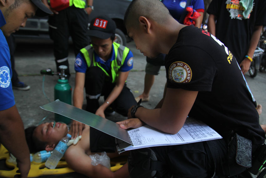 Jason Paulo, prop man of Tribong Grandehanon from Catalunan Grande, Davao City, one of the entries during the Indak- Indak sa Kadalanan, is assisted by the personnel of th 911 after he collapsed while they were dancing in the streets around 10 am Saturday. (Ace R. Morandante/davaotoday.com)