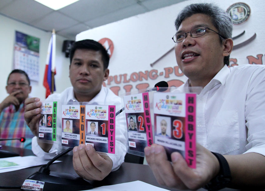 Kadayawan Executive Committee spokesperson Councilor Al Ryan Alejandre and Joseph Lawrence Garcia, assistant information officer of the City Information Office, present the latest identification cards for hobbyist photographers and bloggers, which are numbered to correspond to three designated areas.(Ace R. Morandante/davaotoday.com)
