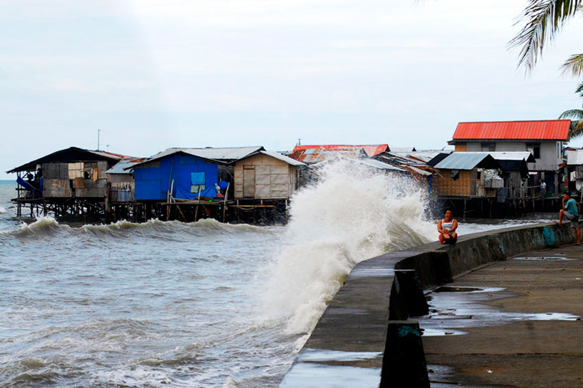 A woman watches strong waves due to bad weather at the breakwaters along Magsaysay Park on Friday morning.(Ace R. Morandante/davaotoday.com)