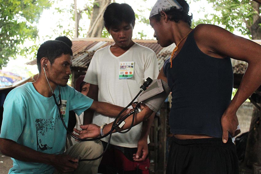 Ata Manobos from Kapalong, Davao del Norte, (from left) Lino Maluhinday and Roy Basid help the medical team during the International Solidarity Mission to Mindanao, who conducted  a medical mission for the lumad evacuees in United Church of Christ in the Philippines Haran Mission Center on Monday.  (Medel V. Hernani/davaotoday.com)