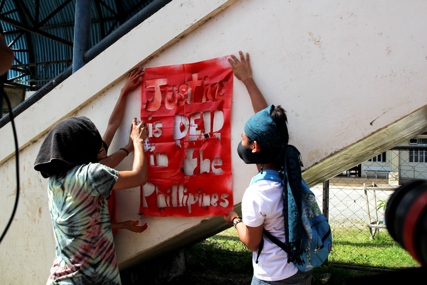 Protesters paint the words "Justice is dead in the Philippines" during the funeral caravan of Emerito Samarca.