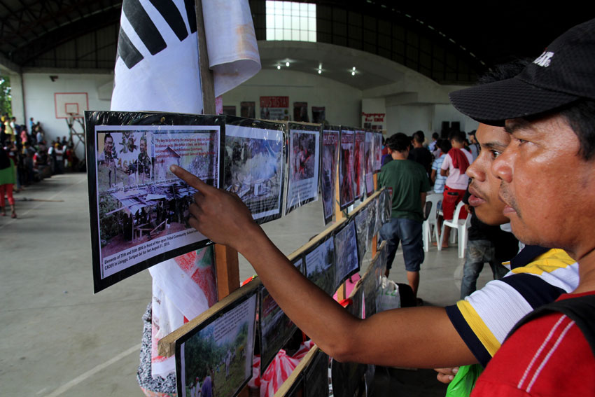 People who visited the wake of Alcadev director Emerito Samarca look at the photos of the "Lianga Massacre" displayed in the Capitol Gym in Butuan City.