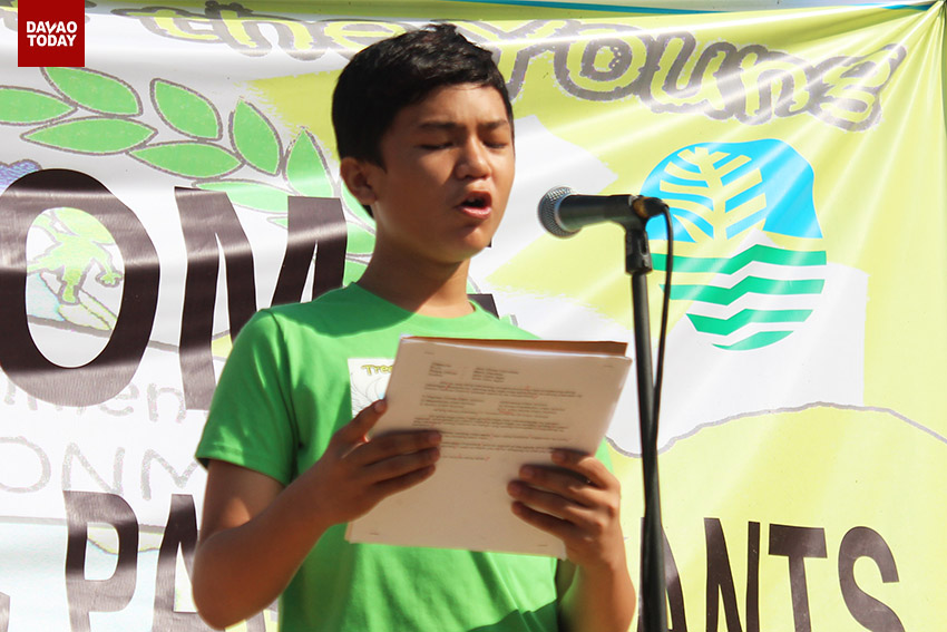 Jirojunn Juri Lopoz, Supreme Pupil Government Federation President of Davao Central District, reads his message on stage before the tree planting activity in Barangay Tigatto, Buhangin, Davao City, on Wednesday morning. (Medel V. Hernani/davaotoday.com)