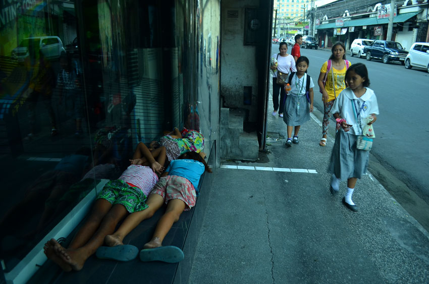 Street children sleep beside the computer shop along Ponciano Reyes Street, while school children go home from school. (Ace R. Morandante/davaotoday.com)