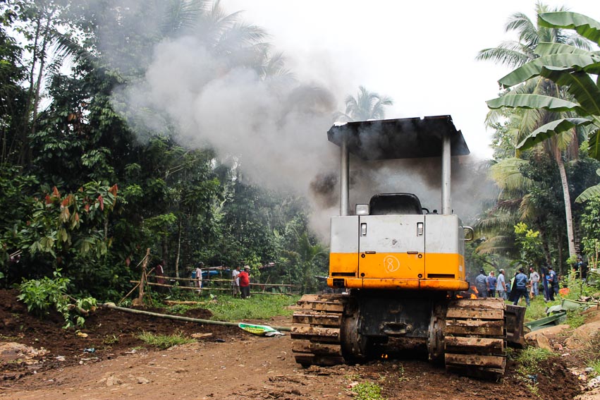 A bulldozer burns after being hit by a molotov cocktail thrown by a resident of Sitio 117 in Bago Oshiro, Tugbok District on Monday morning. A yet to be identified resident threw the improvised bomb in the midst of the chaos that ensued between police forces and the residents after the latter barricaded the area to stop the ongoing construction of the UP-Manambulan Road. (Paulo C. Rizal/davaotoday.com)
