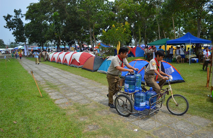 PEDAL. A scout pedals a mechanical tricycle carrying gallons of drinking water for the consumption of their whole camp.