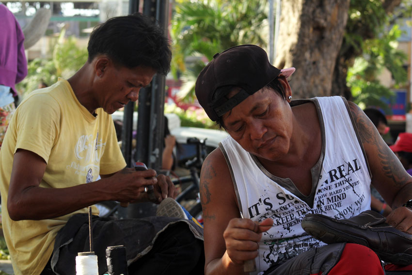 These two shoe repairmen are busy repairing shoes along San Pedro Street in Davao City. Repair in the streets costs P30-P50 per pair for minimal repairs and as much as P200 depending on the repair work needed.  (Ace R. Morandante/davaotoday.com)