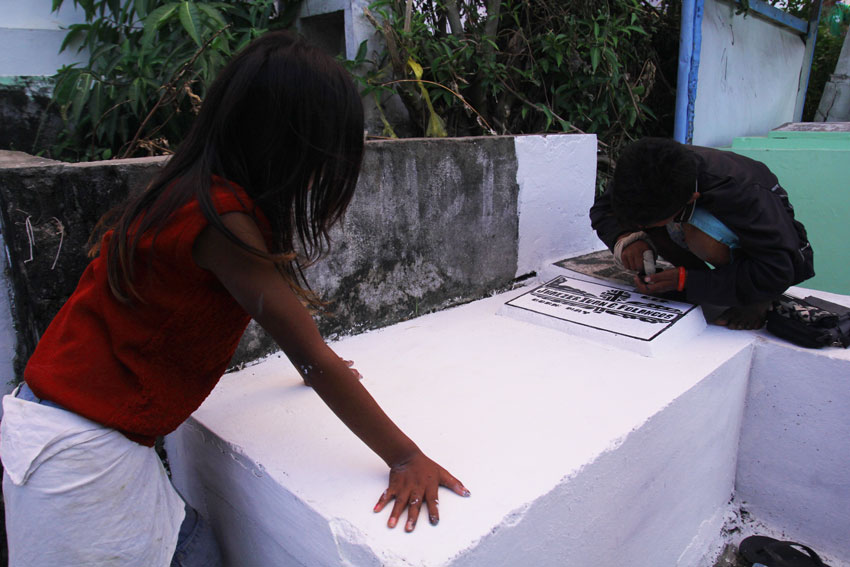 These kids are taking their time to get income during the All Saints' Day at Wireless Public Cemetery. They are paid P30 for repainting the grave stone of the deceased family members of their customers. (Ace R. Morandante/davaotoday.com)