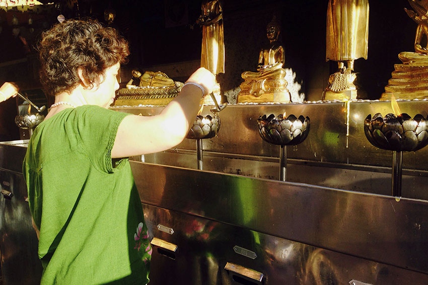 A woman offers her respect to Buddha by pouring hot oil to keep the light aflame. After pouring oil, the worshippers offer their prayers and drops coins inside the cart.