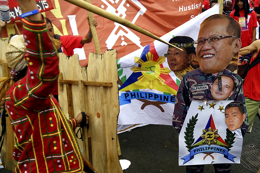ON POINT. In a cultural act, tribal leaders from Manilakbayan protesters, spread photos of military generals and that of President Aquino in front of Camp Aguinaldo, Monday morning. (Earl O. Condeza/davaotoday.com)