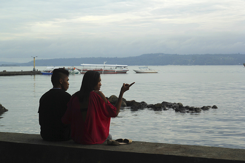 A gay couple sit at a seawall as they watch the sea stretching to Samal Island resort. (Ace R.Morandante/davaotoday.com)