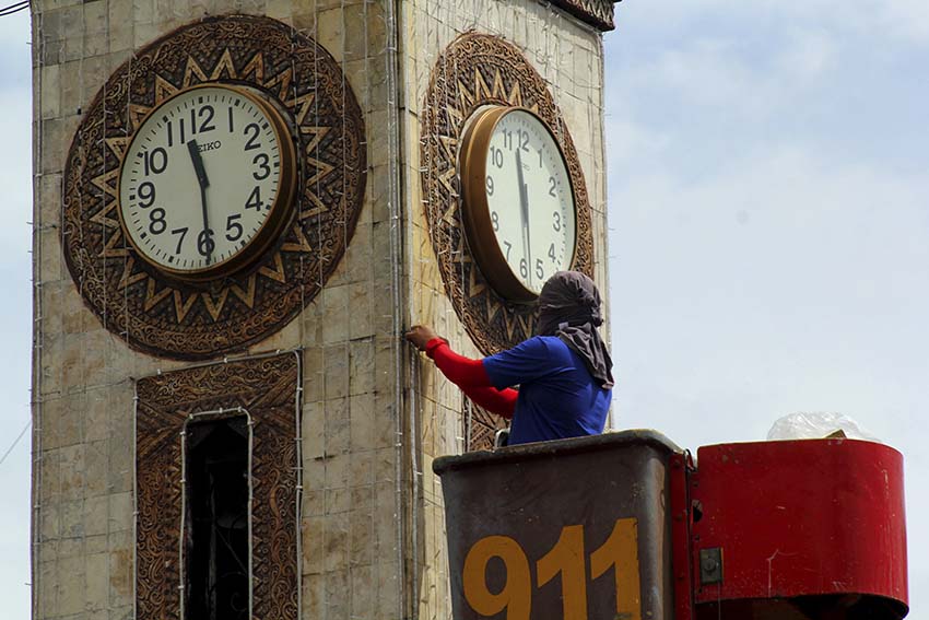 A worker from Davao City General Services Office decorates with Christmas lights the clock tower along San Pedro Street in Davao City. The clock tower displays a giant colorful torch during night time. (Ace R. Morandante/davaotoday.com)