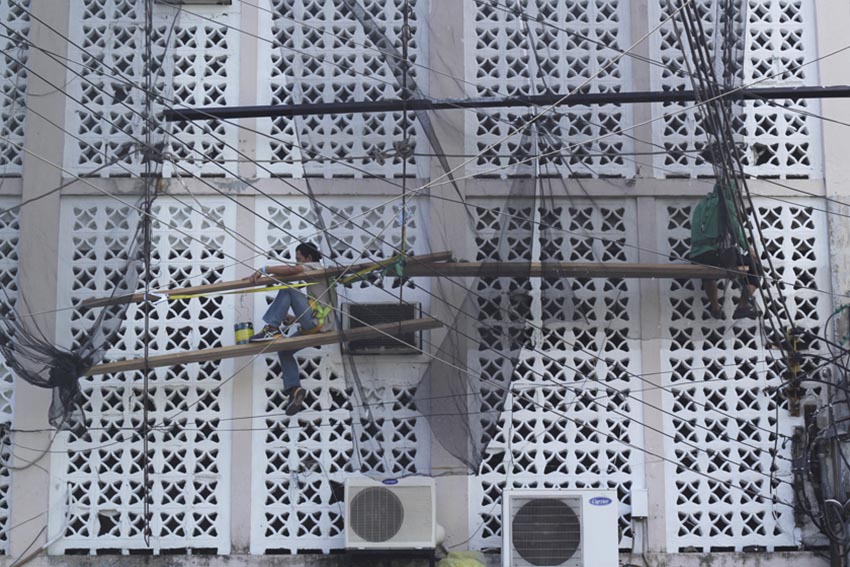 Workers paint the side of one of the buildings of a university using makeshift ladder along Bonifacio Street in Davao City. (Ace R.Morandante/davaotoday.com)