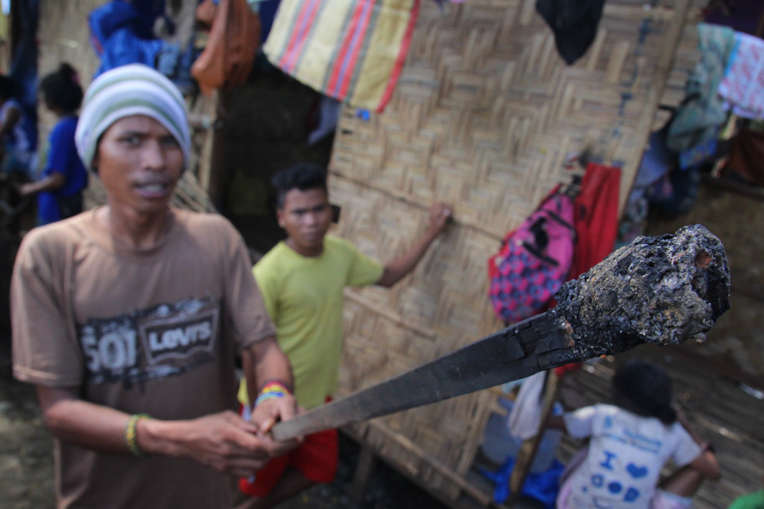 A Lumad shows the torch that was used to burn the UCCP Haran evacuation shelter. (Photo by Ace Morandante/davaotoday.com)