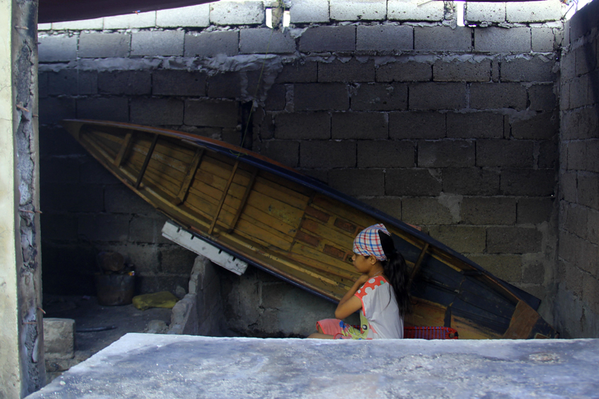 A fisherman's daughter waits for her father who will be bringing materials handy for the rebuilding of their home, after a fire razed their community in Barangay 31-D, Davao City on March 21. The fire burned to ground all their belongings, except for her father's boat. (Ace R. Morandante/davaotoday.com)