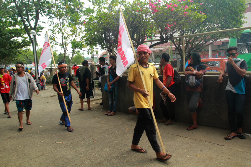 Workers hold the flag of party-list Anakpawis, while waiting to start the march.