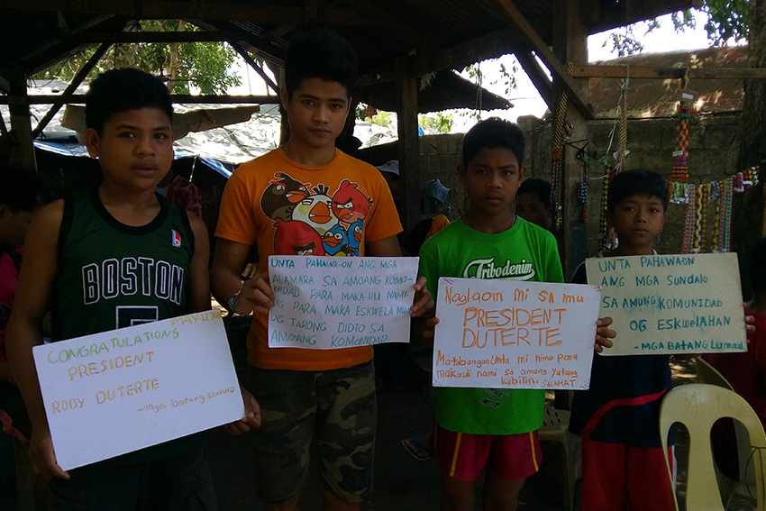 Lumad students, who  are holding classes inside the evacuation center at the UCCP Haran in Davao City, show their messages  to   P resident-elect Rodrigo Duterte. The students called for the pullout of military troops and paramilitary group from their communities. (Earl O. Condeza/davaotoday.com)