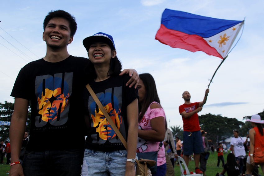 COUPLE SHIRT. A couple wear Duterte shirts is enjoying the performances during the thanksgiving party for President-elect Rodrigo Duterte. On their background is a man waving the Philippine flag. 