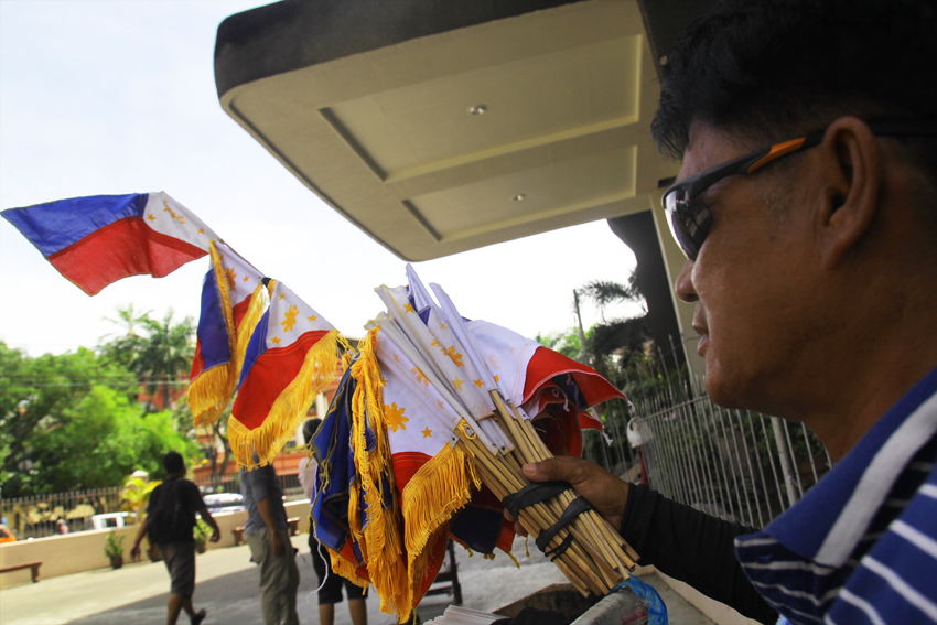 A person with disability displays mini Philippine flags outside the San Pedro Church, Saturday noon. Tomorrow is the 118th commemoration of the Philippine independence.(Ace R. Morandante/davaotoday.com)