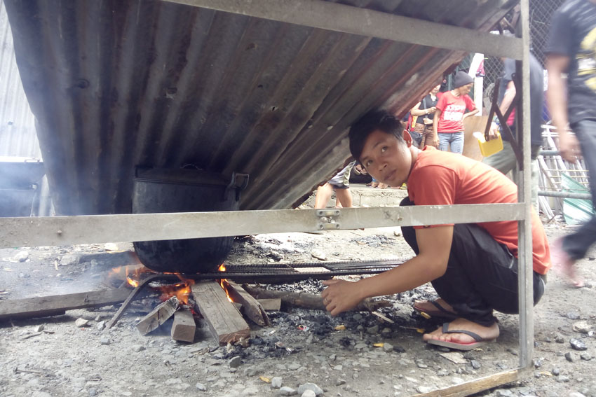 COOKING RICE. A delegate of the caravan rally dubbed Manilakbayan sa SONA cooks rice under an aluminum roofing sheet inside the Department of Agrarian Reform multipurpose gym in Quezon City as rain pours. The delegates attended the rally held during the first State of the Nation Address of President Rodrigo Duterte on Monday, July 25. (Earl O. Condeza/davaotoday.com)