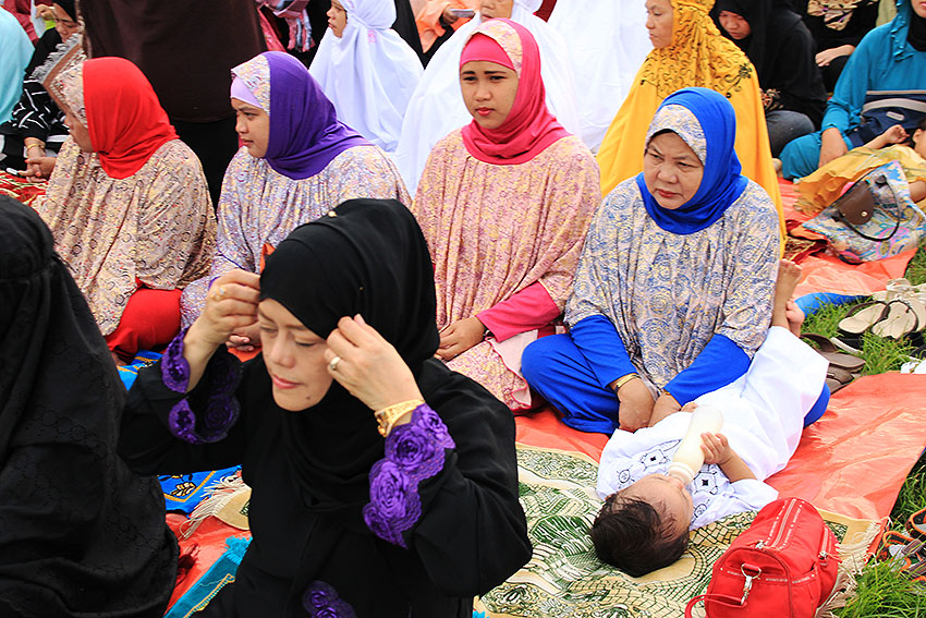 Ranging from the plain simple to the elaborate, Muslim women don their hijab as they join the gathering. They find their places separate from the men at the back of the large group.