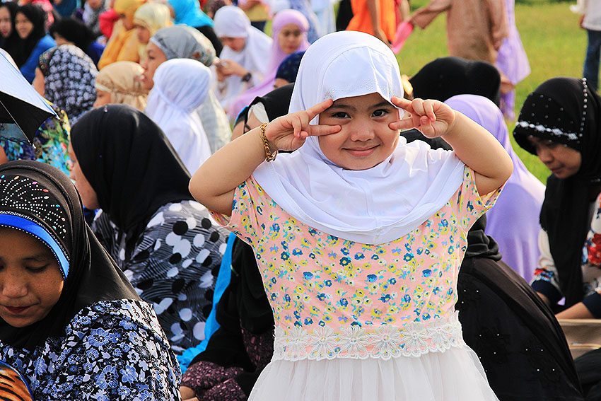 A young Muslim girl poses for the camera while the ceremony is going on.