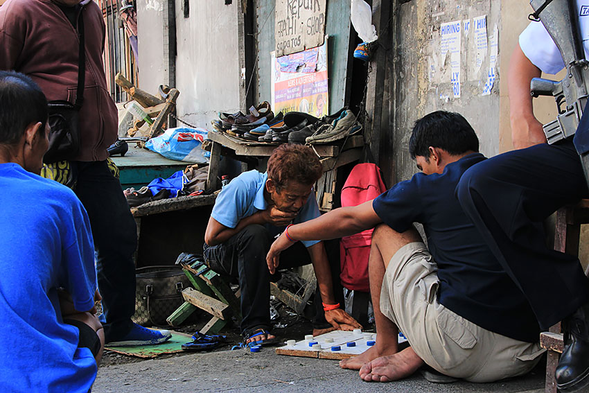 A shoe repairman plays checkers with a friend while waiting for customers near San Pedro Cathedral here, in Davao City. (Paulo C. Rizal/davaotoday.com)