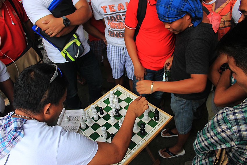 CHESS MATCH. Passersby converge and place their bets on a chess match being played on one of the sidewalks in San Pedro Extension, Davao City. (Paulo C. Rizal/davaotoday.com)