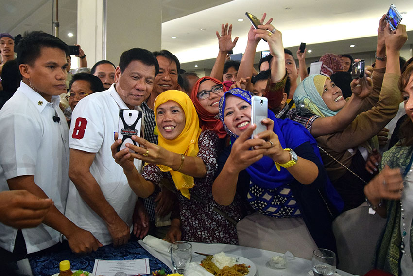 President Rodrigo Duterte poses with a delegate of the Mindanao Hariraya Eid'l Fitr 2016 at the SMX Convention Center, SM Lanang in Davao City on Friday, July 8. The event was attended by an estimate of 700 Mindanao Muslim leaders and other guests. (Presidential Photographers Division) 