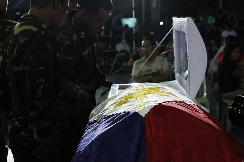 KILLED IN ACTION. Soldiers look on at the corpse of Pfc. Rolen Roy C. Sarmiento, one of the soldiers who died in a series of offensives by the 8th Pulang Bagani Company of the New People's Army in Monkayo Town, Compostela Valley. Sarmiento, along with three others are currently laid at state at Camp Apolinario, in Panacan, Davao City. (Paulo C. Rizal/davaotoday.com)