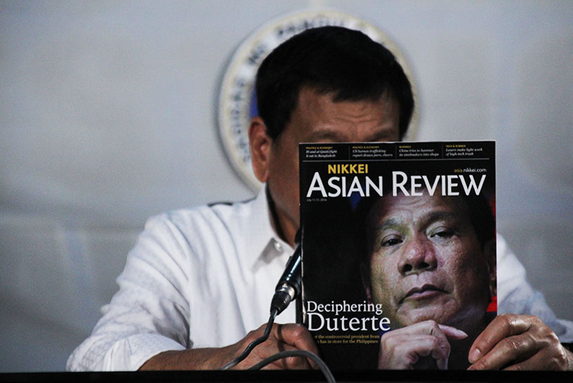 President Rodrigo Duterte reads the back cover of a copy of Nikkei Asian Review magazine, which features him in the cover story. (Paulo C. Rizal/davaotoday.com)
