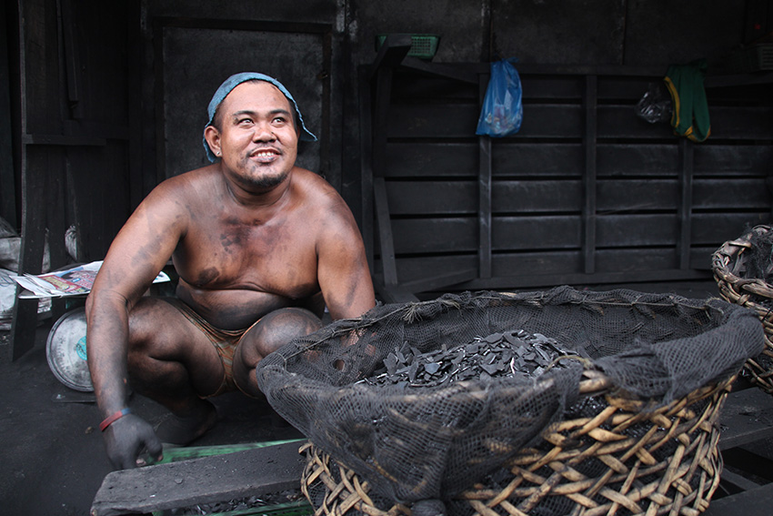 Mark Casipi, 27, sells charcoal in Davao City's Bangkerohan Public Market for 13 years now. Casipi says it is hard to earn during the months of September to December as the business is affected by the rainy season. He sells 10 to 15 sacks of charcoal per day and earns P4 per kilo. (Paulo C. Rizal/davaotoday.com)