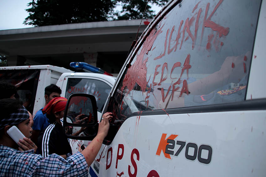 A protester smears a police car with the words "JUNK EDCA VFA", which stand for the two agreements signed between US and the Philippines, Enhanced Defense Cooperation Agreement and Visiting Forces Agreement, during a protest that met a violent dispersal on Wednesday, Oct. 19. The same police vehicle, which would be driven by PO3 Franklin Kho, would run over the protesters an hour later. (Paulo C. Rizal/davaotoday.com)