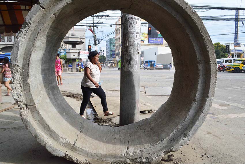 A woman streches her feet while walking across the corner of Magallanes and Torres Street, Davao City, which undergo road improvement. (Medel V. Hernani/davaotoday.com)