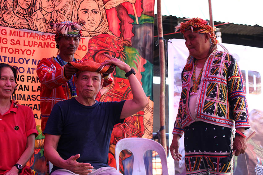 Datu Monico Cayog and Isidro Indao of Kusog sa Katawhang Mindanao puts on a bandana called a 'Tangkulo,' on National Democratic Front peace panel member, Benito Tiamzon on Wednesday, Oct. 26. Traditionally worn by baganis (tribal warriors), the Tangkulo expresses the Lumad's gratitude towards Tiamzon and the NDFP's support for the plight of the indigenous and Moro people. (Paulo C. Rizal/davaotoday.com)