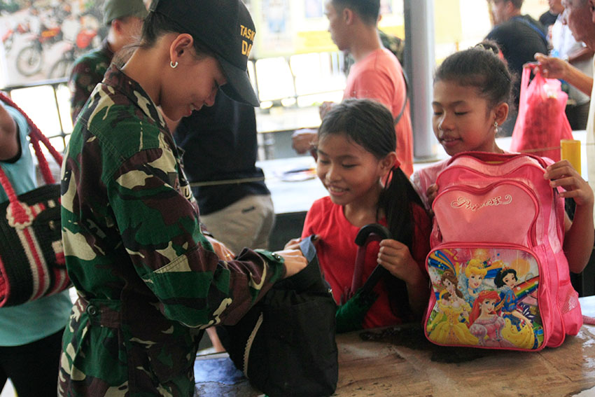 Two girls here cannot contain their excitement to visit their province to take part in the observance of the All Saints' Day as a female Task Force (TF) personnel inspect their backpacks at the Davao City Overland Transport Terminal (DCOTT) on Monday, Oct. 31. (Maria Patricia C. Borromeo/davaotoday.com)