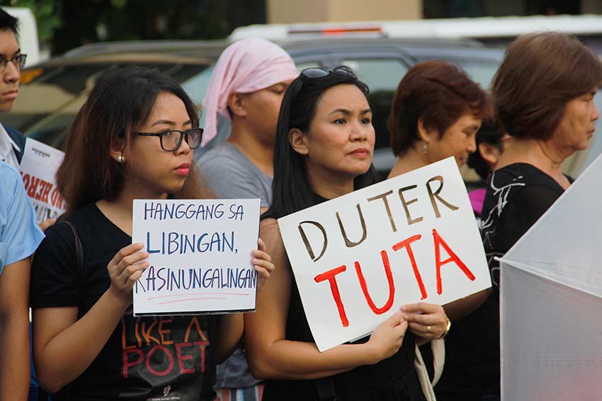 Jhoanna Cruz (right), a professor from the University of the Philippines Mindanao, carries a placard criticizing President Rodrigo Duterte as a "lapdog" over the issue of the hero's burial for the late dictator Ferdinand Marcos. Cruz is among those who protested in Davao City against Marcos burial. (Earl O. Condeza/davaotoday.com)