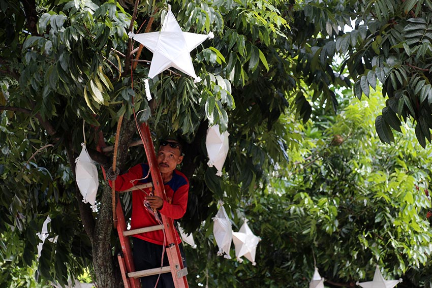 A government employee installs Christmas decorations along Roxas Avenue, Davao City. The lanterns, locally called as parol will be lit every night starting Dec. 1. (Paulo C. Rizal/davaotoday.com)