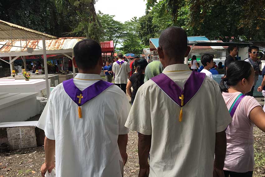 Two Roman Catholic lay ministers make their rounds inside the Davao Penal and Prison Farm Colony cemetery to bless the tomb in exchange for a fee during the annual observance of Undas. (Mart D. Sambalud/davaotoday.com)