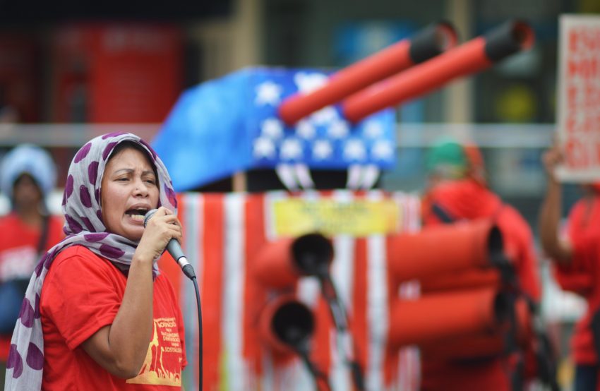 Catherine Culiao of Sining Obrero, an artist group composed of workers, sings a song that is about opposing the US' military bases in the country during a rally that commemorates the 153rd birth anniversary of national hero Andres Bonifacio. Behind her is an effigy of tank that symbolizes US military intervention. (Medel V. Hernani/davaotoday.com)