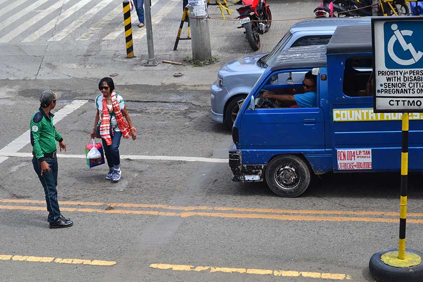 PRIORITY LANE. A traffic enforcer aids an elderly as she crosses along J.P. Laurel Avenue in Davao City in a special lane allotted only for persons with disability, senior citizens, and pregnant women. (Robby Joy Salveron/davaotoday.com)