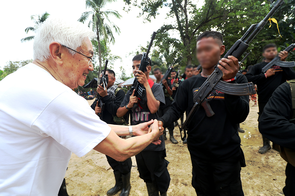 Luis Jalandoni, National Democratic Front senior adviser, shakes hands with a guerrilla fighter of the New Peoples' Army the morning after the 48th founding anniversary of the Communist Party of the Philippines in Barangay Lumiad, Paquibato district on Tuesday, Dec. 27 . (Jaja Necosia/Breakaway Media)