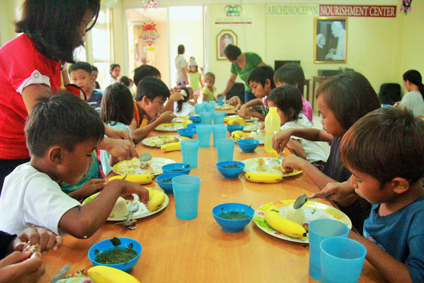 FREE LUNCH. Children enjoy eating their free lunch given by the Archbishop Nutrition Council during a regular nutritional status monitoring on Wednesday, Dec. 7 in Pag-asa Street, Davao City. Parents blame poverty and lack of job as the main reason why some of them could not afford to give their children proper nutrition. (Maricar Emata/davaotoday.com)