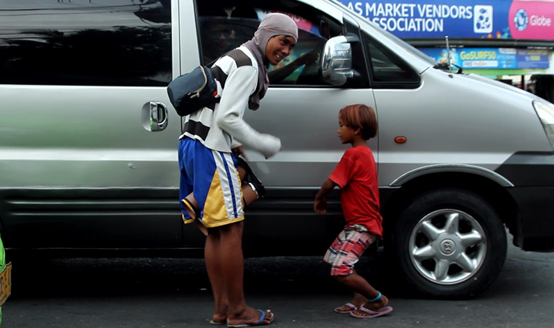 A young man plays his makeshift drums while his brother dances to the tune in exchange for some loose change in Ulas, Davao City on Wednesday afternoon, Dec.21. (Paulo C. Rizal/davaotoday.com)